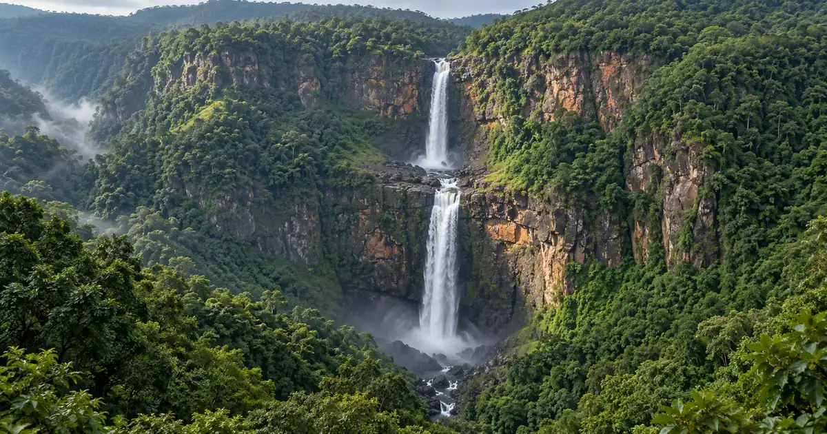 Illustrative two-tier waterfall dropping through a forested cliff in Similipal