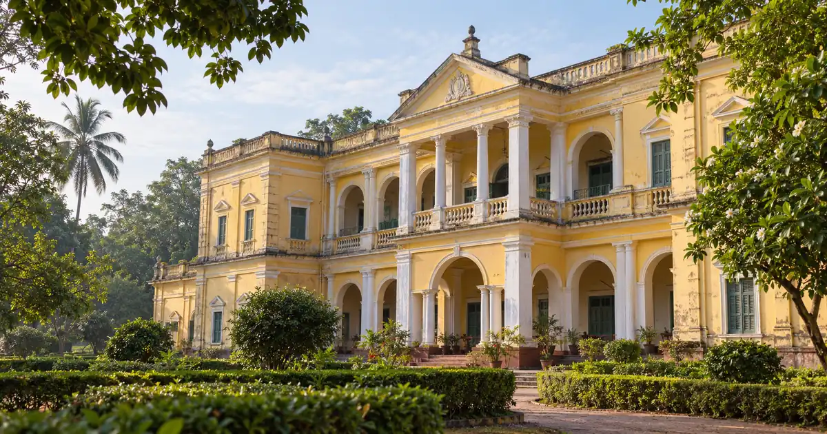 Yellow facade and white columns of Belgadia Palace above a shaded garden