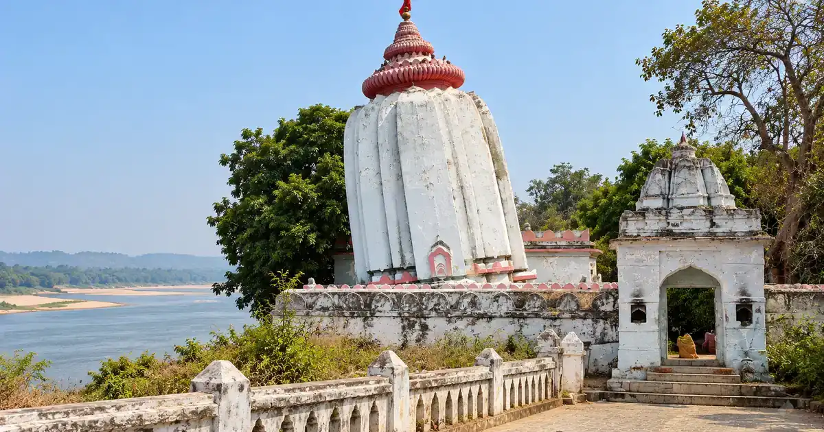 Visibly leaning whitewashed shikhara of Huma Temple beside the Mahanadi River in Sambalpur