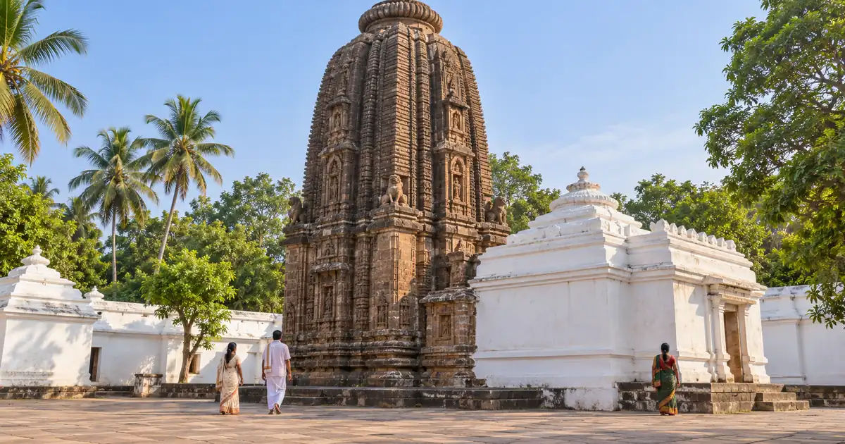 Dark Kalinga stone tower and whitewashed courtyard walls of Sakhigopal Temple near Puri