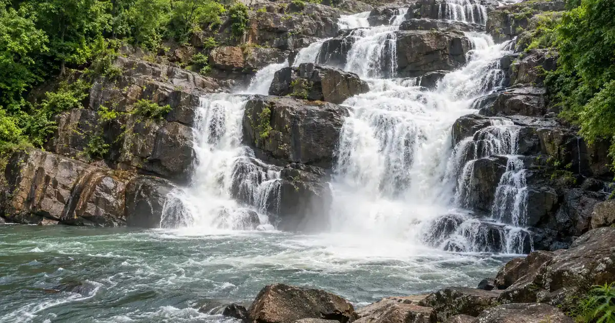Stepped cascade at Sanaghagara Waterfall viewed from a safe forest-side lookout
