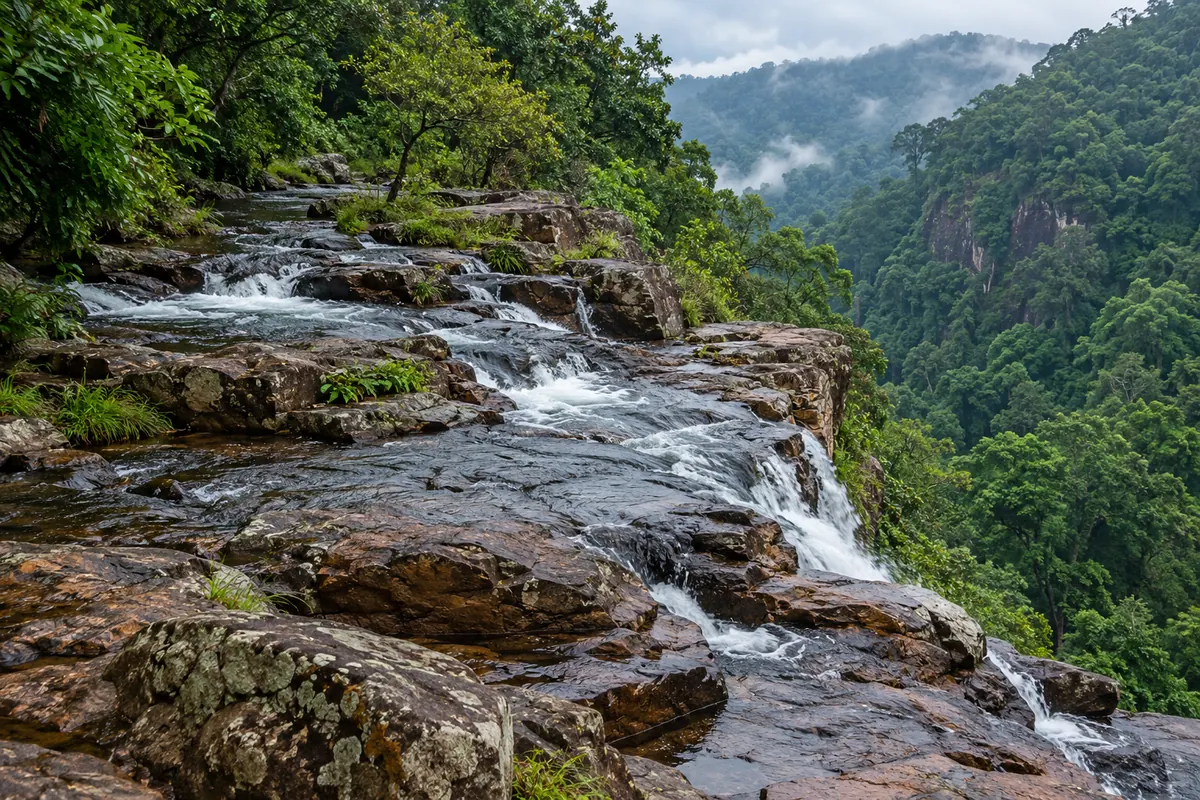 Illustrative rocky stream spilling over ledges into a forested gorge in Similipal