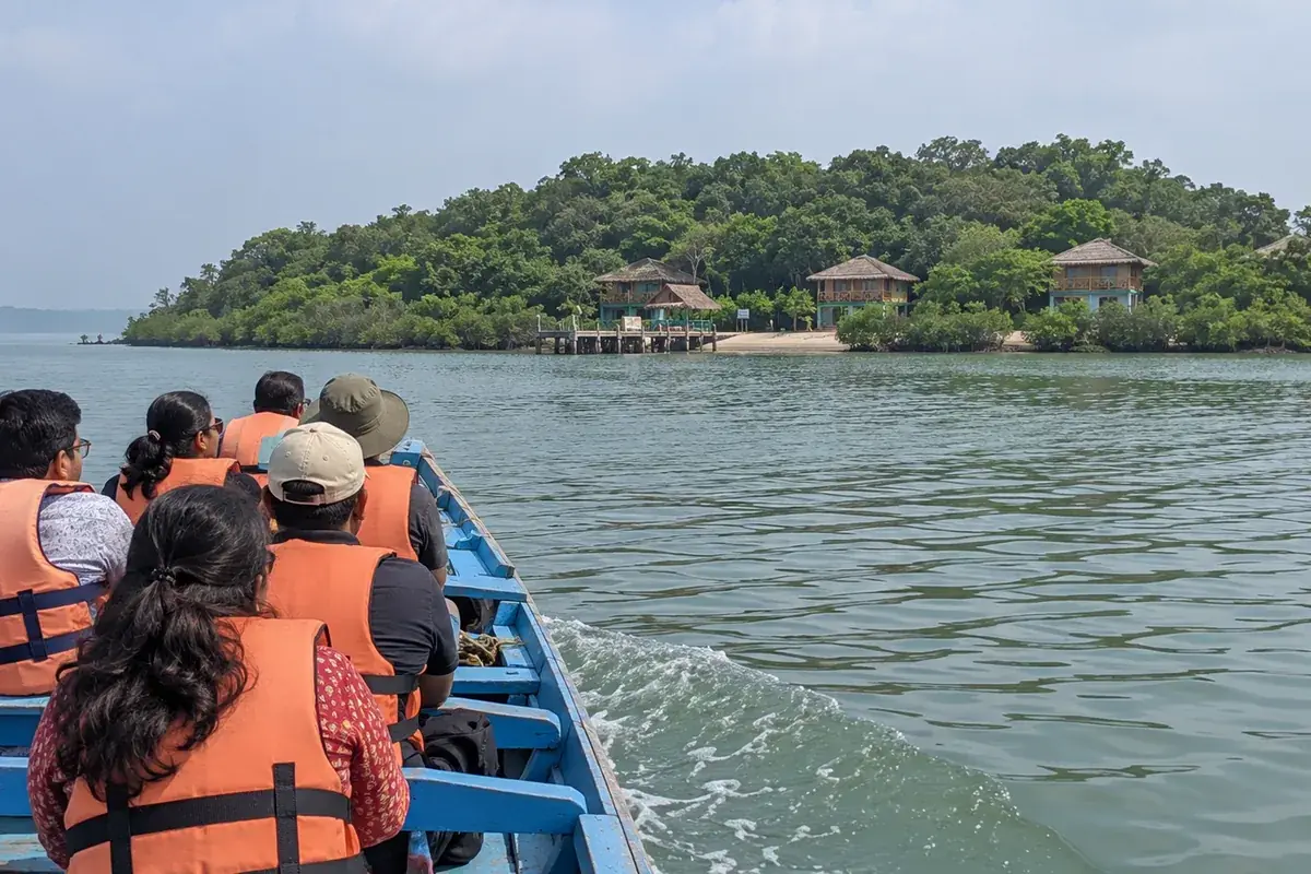 Passenger boat crossing Chilika Lagoon toward a wooded island camp