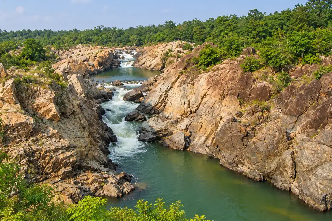 Pale granite boulders surround a green pool in the Bhimkund gorge