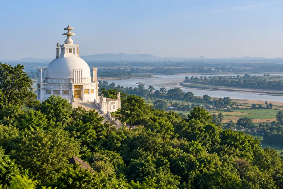 The white Peace Pagoda stands on the green Dhauli hillside