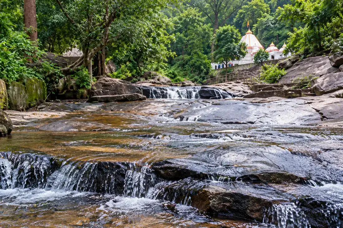 Shallow water runs over granite slabs beside Harishankar Temple
