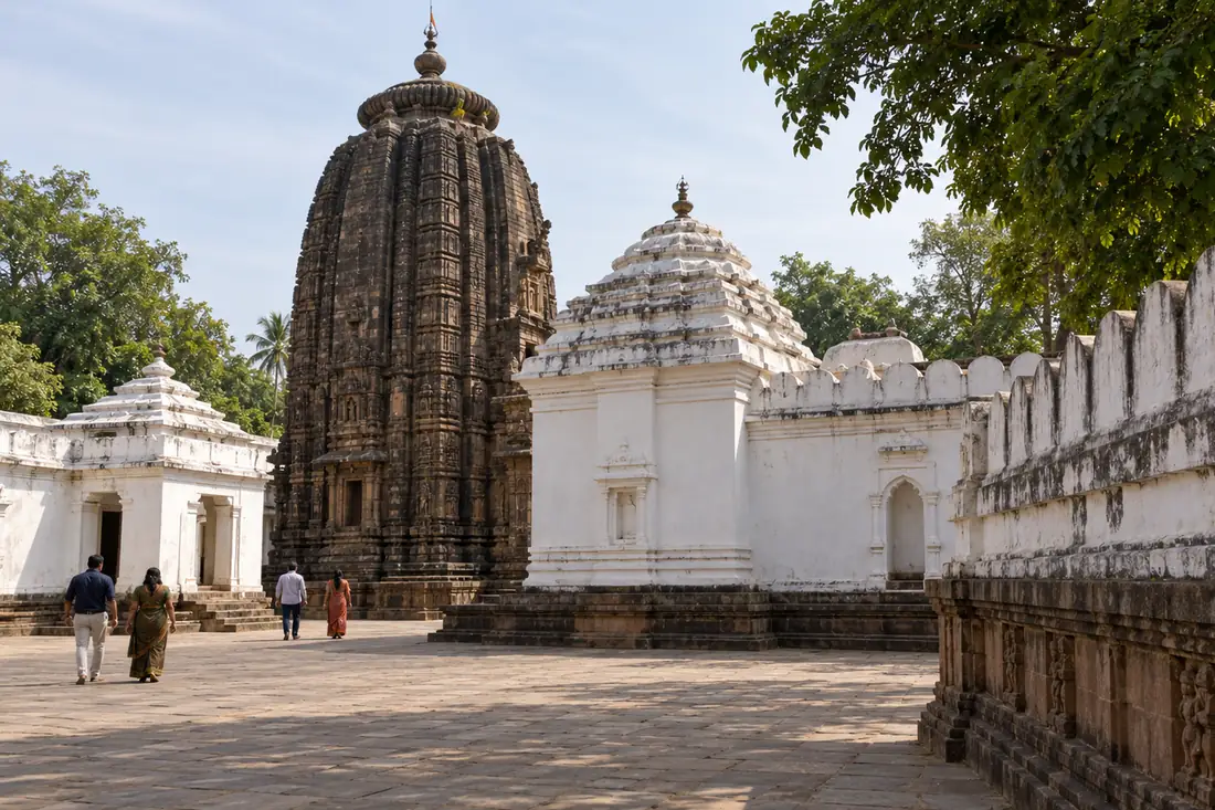 Visitors walk through the courtyard below Sakshi Gopal Temple’s dark stone tower